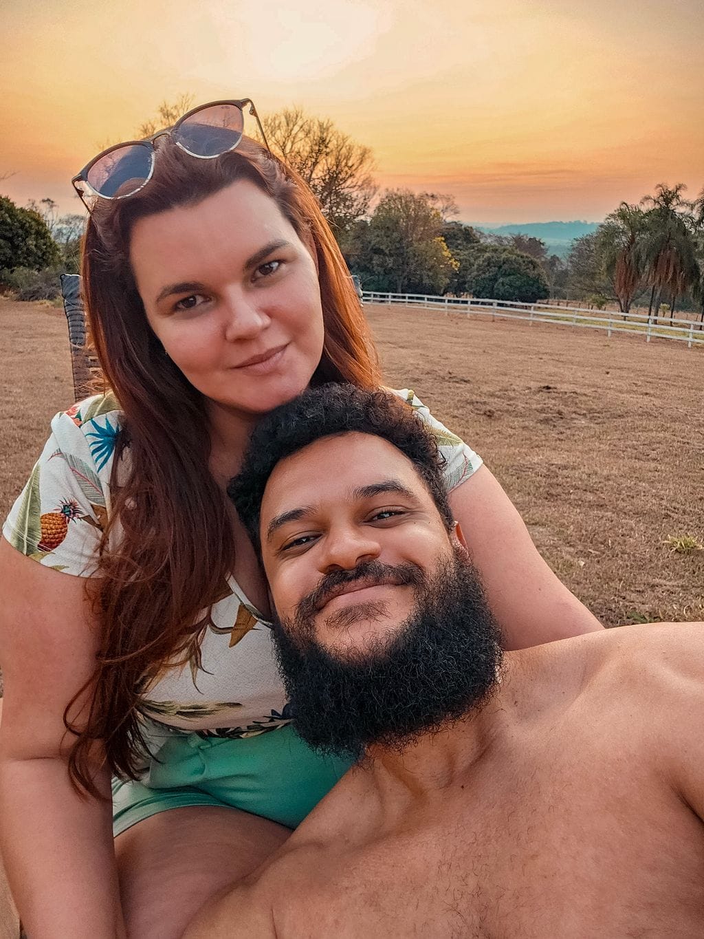 Claudemir e sua parceira sorrindo juntos no campo ao entardecer